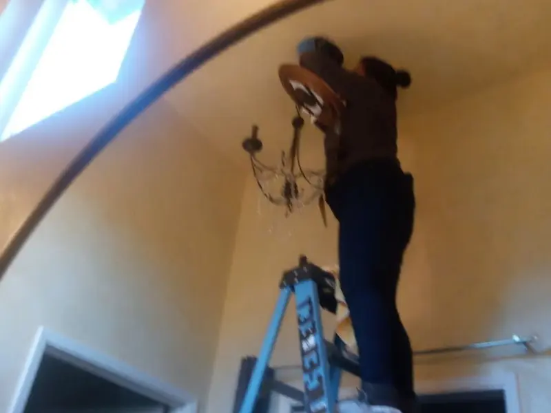 Electrician installing a chandelier in a Sudbury residence